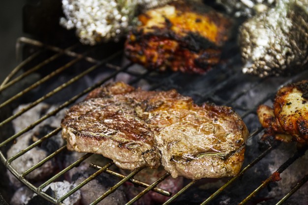 tasty-fresh-appetizing-meat-beef-on-grill-cooking-on-open-fire-on-grill-grid-nature-background-closeup_1220-1378