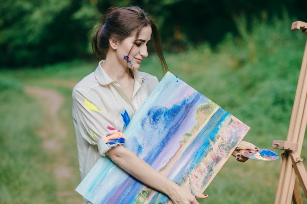 woman-with-paint-stained-t-shirt-with-a-picture-in-her-hand_1157-2274