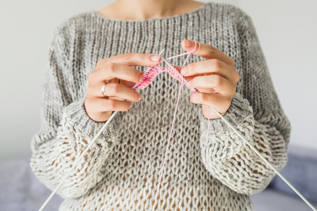 mid-section-view-of-a-woman-s-hand-crocheting-with-pink-thread_23-2147875075